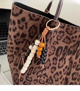 Nahaufnahme eines bunten Holzperlen-Anhängers mit goldenem Verschluss an einer Leoparden-Tasche