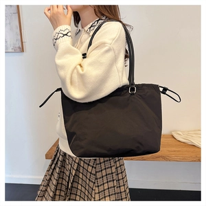 Detail view of black drawstring tote bag with smooth leather handles for daily commute