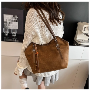 Brown suede tote bag with leather straps and tribal tassel detail in lifestyle setting