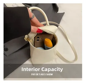 Détail montrant la capacité interne du sac bandoulière cylindrique crème avec téléphone et crème