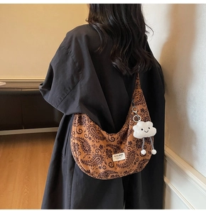 Detail der Vintage-Paisley-Schultertasche mit einem süßen weißen Plüschwolken-Anhänger