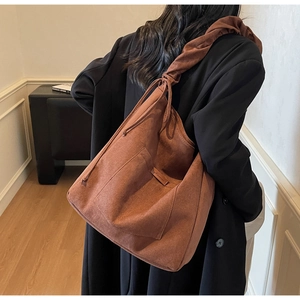 Brown suede bucket bag with side drawstring showing large capacity for daily use