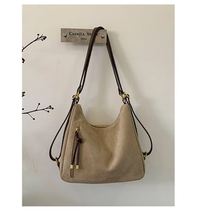 Close-up of matte suede backpack with brown straps and elegant gold hardware accents