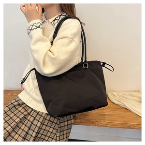 Close-up of minimalist black nylon tote bag with decorative side drawstrings on model