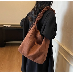 Detail view of brown suede tote bag featuring a stylish knotted strap and drawstring sides