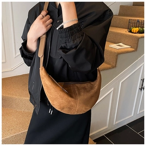 Brown frosted suede crescent bag shown in a lifestyle setting on stairs