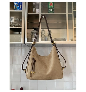 Close-up of vintage khaki suede shoulder bag with brown leather strap and long tassel detail