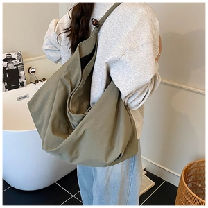 Détail du cabas en toile vert olive avec un nœud décoratif et une perle en bois foncé