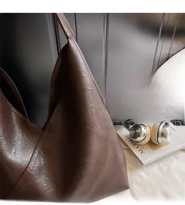 Close-up of brown litchi pattern leather tote bag with laptop and headphones