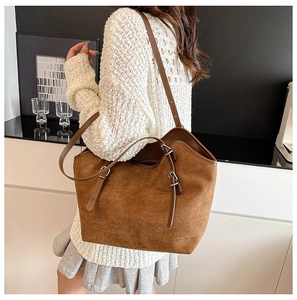 Detail of matte brown leather tote bag with adjustable silver buckle and fine stitching