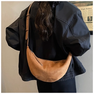 Detail view of a vintage brown orange suede crescent crossbody bag worn by a model