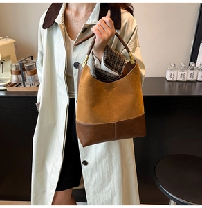 Detail of suede and smooth leather stitching on a retro brown bucket tote bag