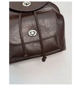 Detail of dark brown leather bag showing silver metal swivel lock and natural texture