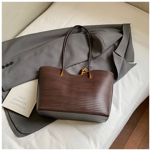 Vue détaillée du sac cabas tressé marron foncé avec attaches métalliques dorées