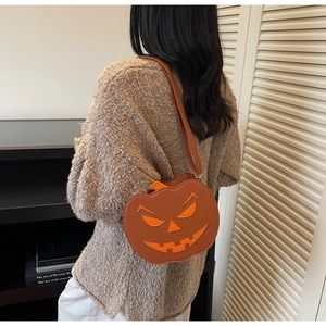 Detail of pumpkin-shaped crossbody bag featuring a funny face and PU leather texture