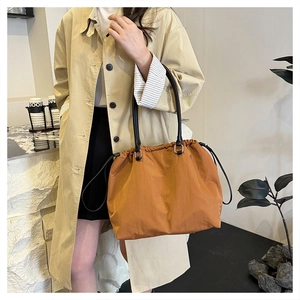 Detail of caramel tote bag featuring drawstring closure and slim leather handles