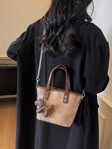 Brown leather crossbody bucket bag with adjustable strap and cute dog pendant accessory