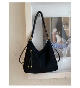 Detail of black vintage suede hobo bag with knotted drawstring and gold metal accents