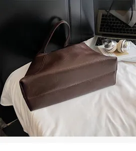 Detailed view of the dark brown tote bag showing its vintage pleated leather texture and strap