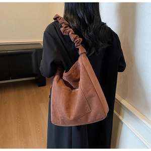 Detail of caramel brown suede tote bag featuring a wide ruffled shoulder strap design