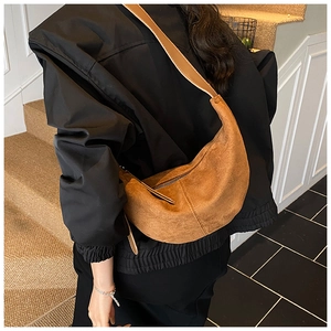 Minimalist caramel suede crescent bag worn by model on stairs, showing crossbody fit