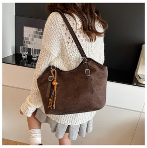 Detail of matte brown tote bag with adjustable silver buckle strap and tassel