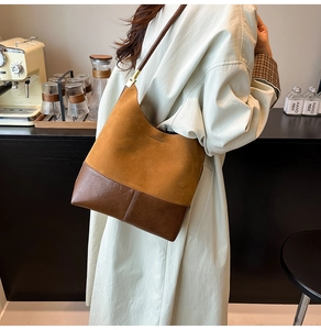 Détail des coutures en daim marron vintage et de la texture cuir d'un sac seau d'épaule