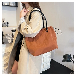 Detail of caramel nylon tote bag with black leather straps and drawstring closure
