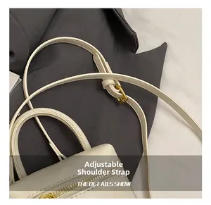 Détail de la bandoulière réglable et de la boucle en métal doré sur le sac en cuir crème