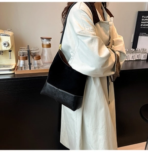 Détail du sac hobo en daim noir et cuir texturé avec accents métalliques dorés