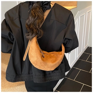 Detailed view of a brown matte leather hobo bag with stitching worn on shoulder