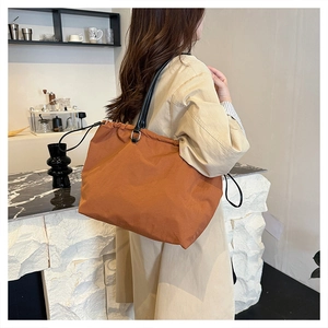 Detail showing caramel nylon tote bag with drawstring closure and slim black straps