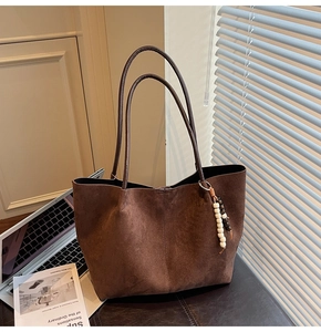 Détail du sac cabas en daim marron avec pendentif en perles ethniques sous le soleil