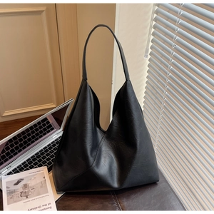 Detail of black pebbled leather tote bag in a minimalist home office setting