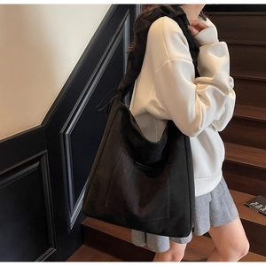 Detail of black large capacity shoulder bag with hobo style and wide strap worn by model