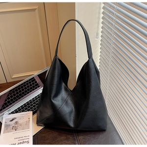 Detail of black pebbled leather hobo tote bag featuring asymmetric triangle panel design