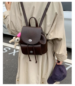 Street style shot of a vintage dark brown mini backpack with drawstring and silver buckles