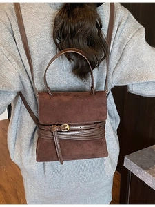 Bolso de hombro vintage marrón oscuro con hebilla decorativa llevado por modelo