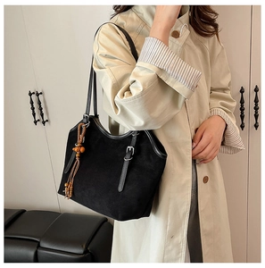Detailed view of black matte tote bag with decorative tassel and wooden beads charm