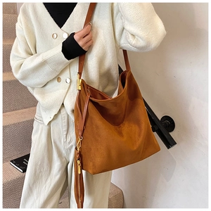 Close-up of brown suede hobo tote bag with long tassel detail and gold hardware