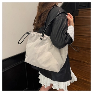 Detail of minimalist cream oversized tote bag with drawstring closure and slim black straps