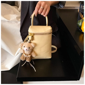 Détail du sac à main jaune crème avec fermeture éclair dorée et breloque ourson