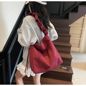Detail of burgundy canvas tote bag featuring ruffled shoulder strap and drawstring pocket