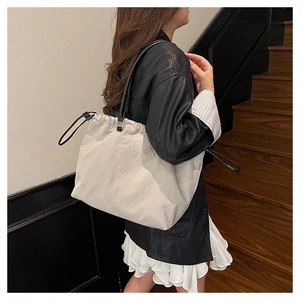 Detailed view of beige tote bag with drawstring closure and black straps on a model