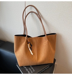 Détail d'un cabas en daim marron avec pendentif en perles de bois et fines anses souples