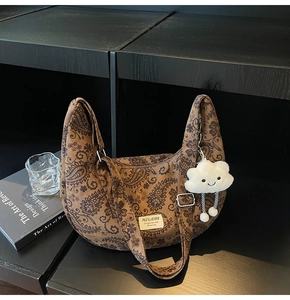 Detailansicht der braunen Retro-Hobo-Tasche mit einem süßen weißen Plüsch-Wolkenanhänger