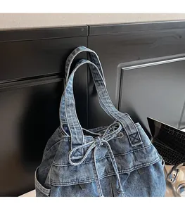 Detail view of light blue denim tote bag with drawstring bow and wide shoulder strap