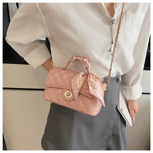 Pink quilted shoulder bag with gold twist lock and silk scarf wrapped on the chain handle