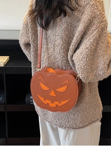 Quirky Halloween pumpkin crossbody bag in brown leather with orange face on a model