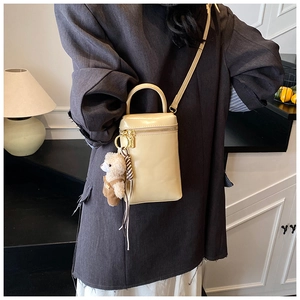 Détail du mini sac beige en cuir brillant avec charme d'ours en peluche et bandoulière